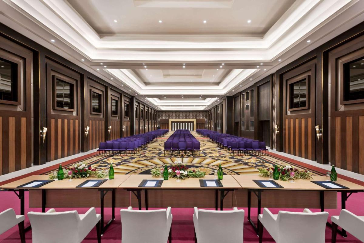 a large conference room with a long table and purple chairs at Ramada by Wyndham Lucknow Hotel and Convention Center in Lucknow