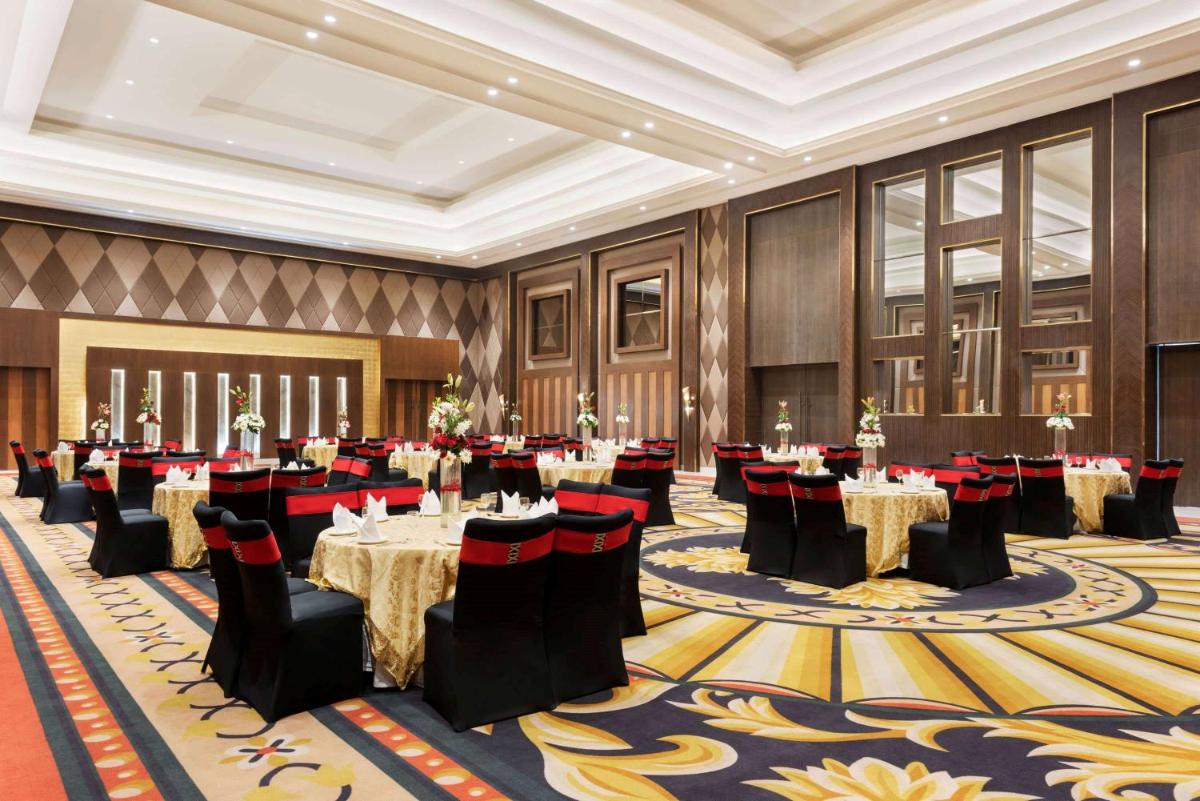 a banquet hall with tables and chairs in a room at Ramada by Wyndham Lucknow Hotel and Convention Center in Lucknow