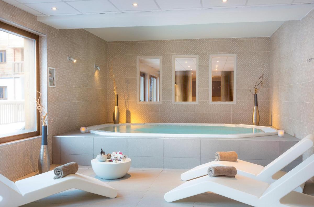La salle de bains est pourvue d'une baignoire et de 2 chaises blanches. dans l'établissement Résidence Club MMV La Clé des Cimes, à Arêches
