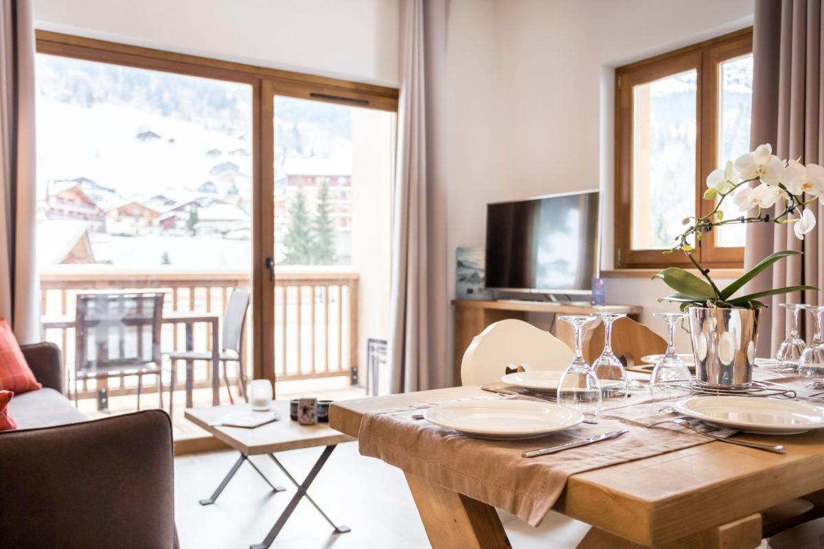 une salle à manger avec une table en bois et un balcon dans l'établissement Résidence Club MMV La Clé des Cimes, à Arêches