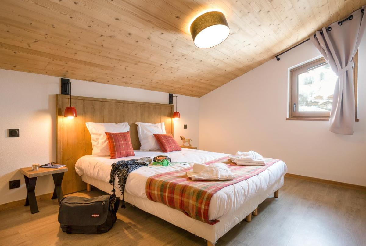 une chambre avec un grand lit avec un plafond en bois dans l'établissement Résidence Club MMV La Clé des Cimes, à Arêches