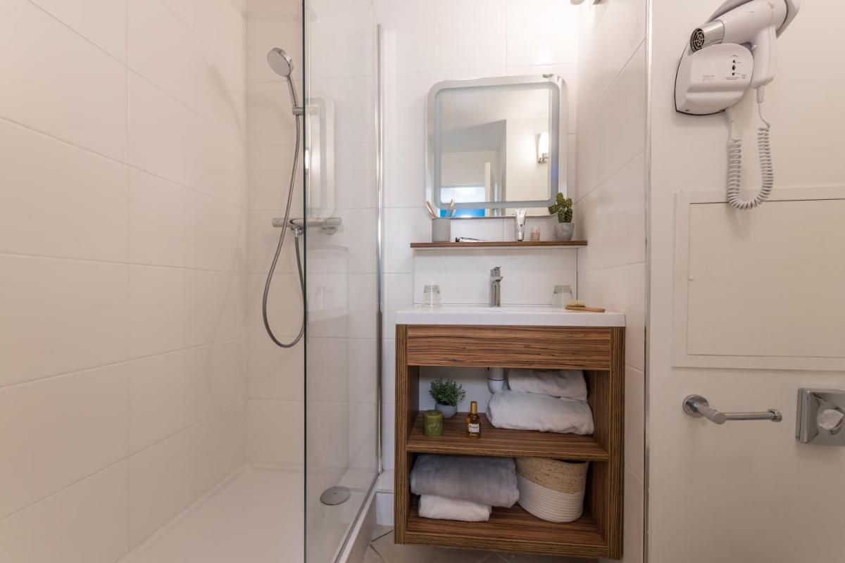 une salle de bain avec un lavabo et une douche avec un miroir dans l'établissement Hôtel de l'Esterel Pierre & Vacances, à Agay