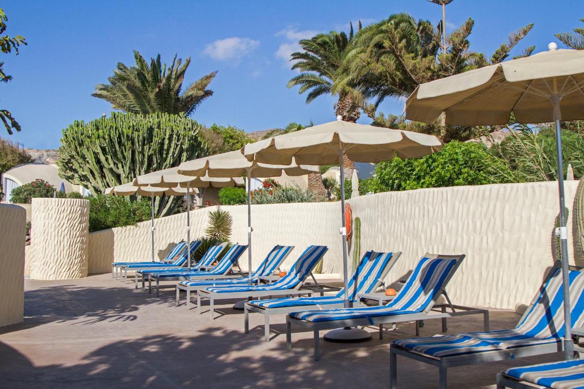 una fila de sillas y sombrillas azules en Hotel LIVVO Risco del Gato Suites, en Costa Calma