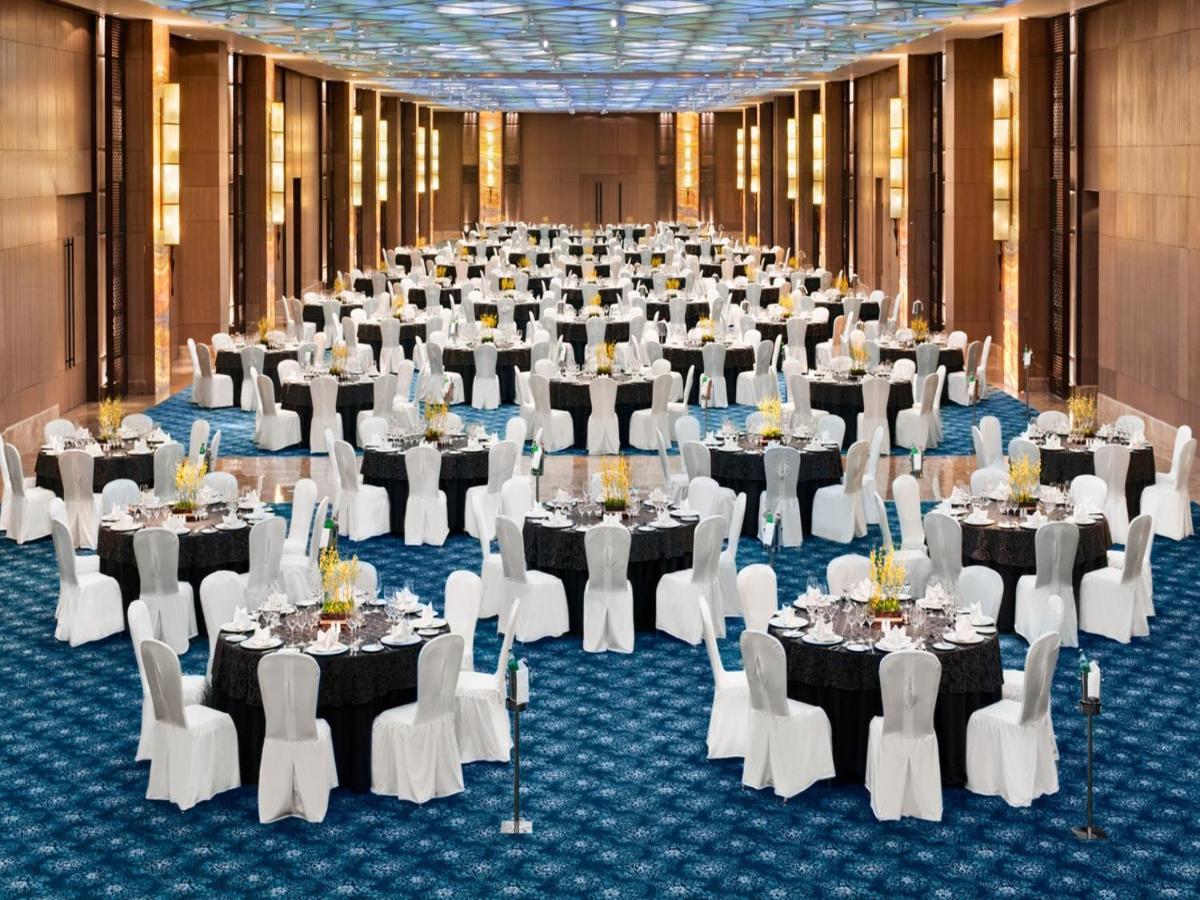 a large banquet hall with tables and white chairs at The Leela Ambience Convention Hotel Delhi in New Delhi