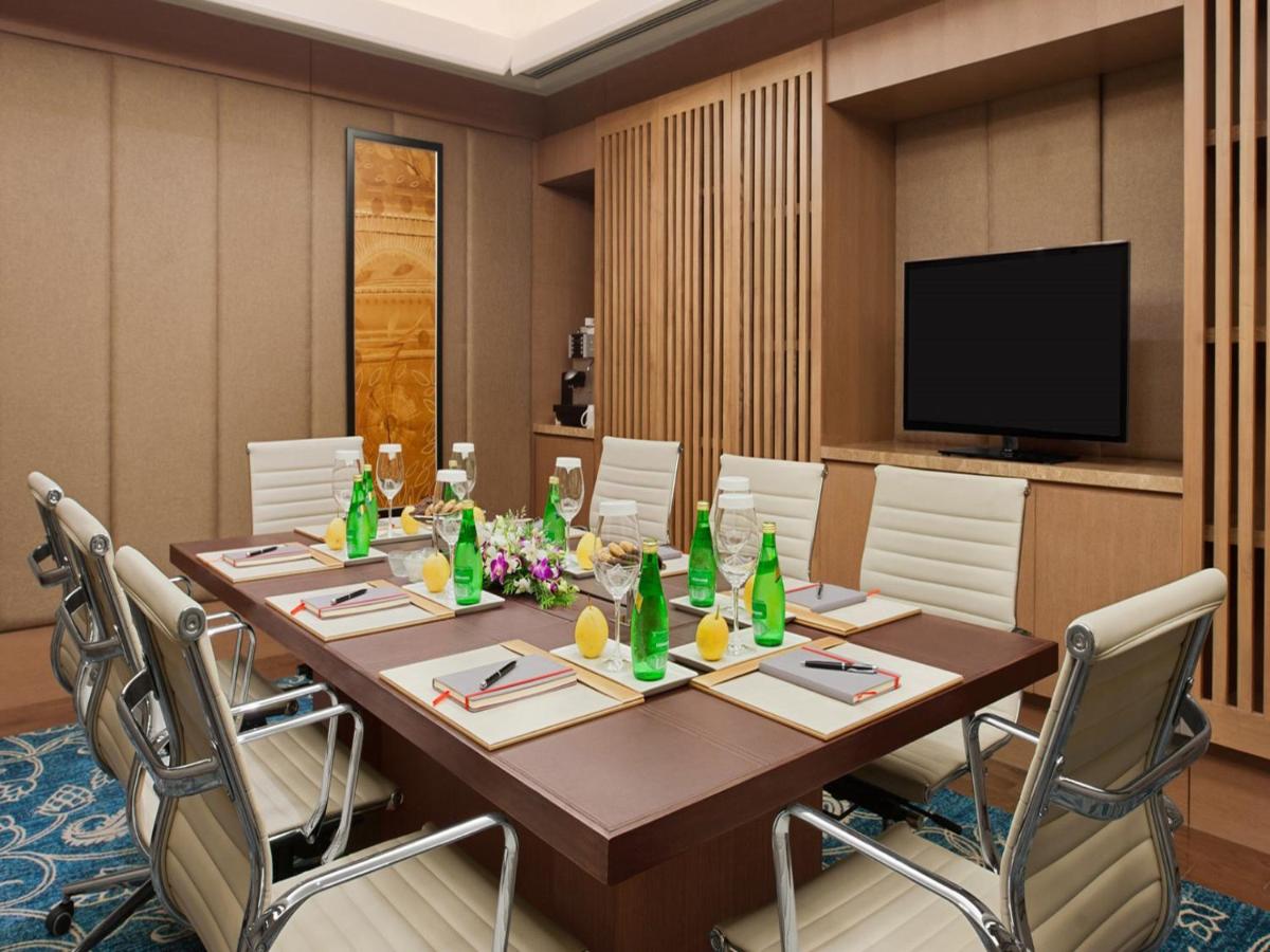 a conference room with a long wooden table and chairs at The Leela Ambience Convention Hotel Delhi in New Delhi