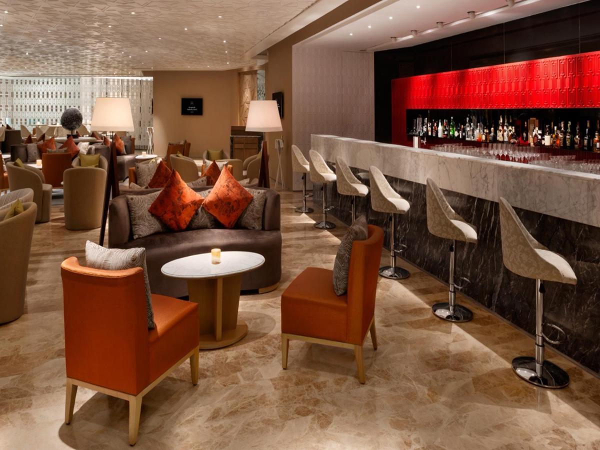 a lobby of a hotel with chairs and a bar at The Leela Ambience Convention Hotel Delhi in New Delhi