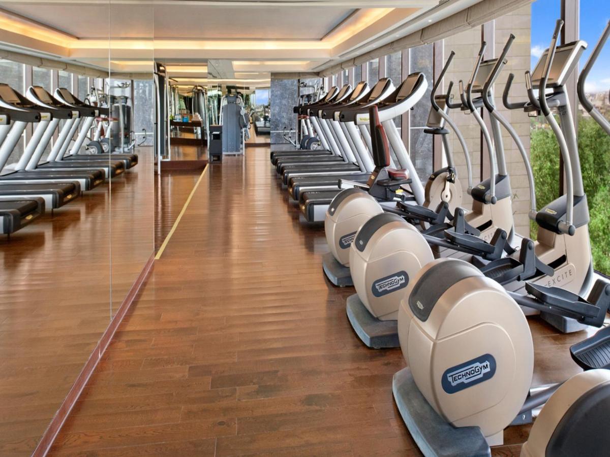 a gym with rows of tread machines at The Leela Ambience Convention Hotel Delhi in New Delhi