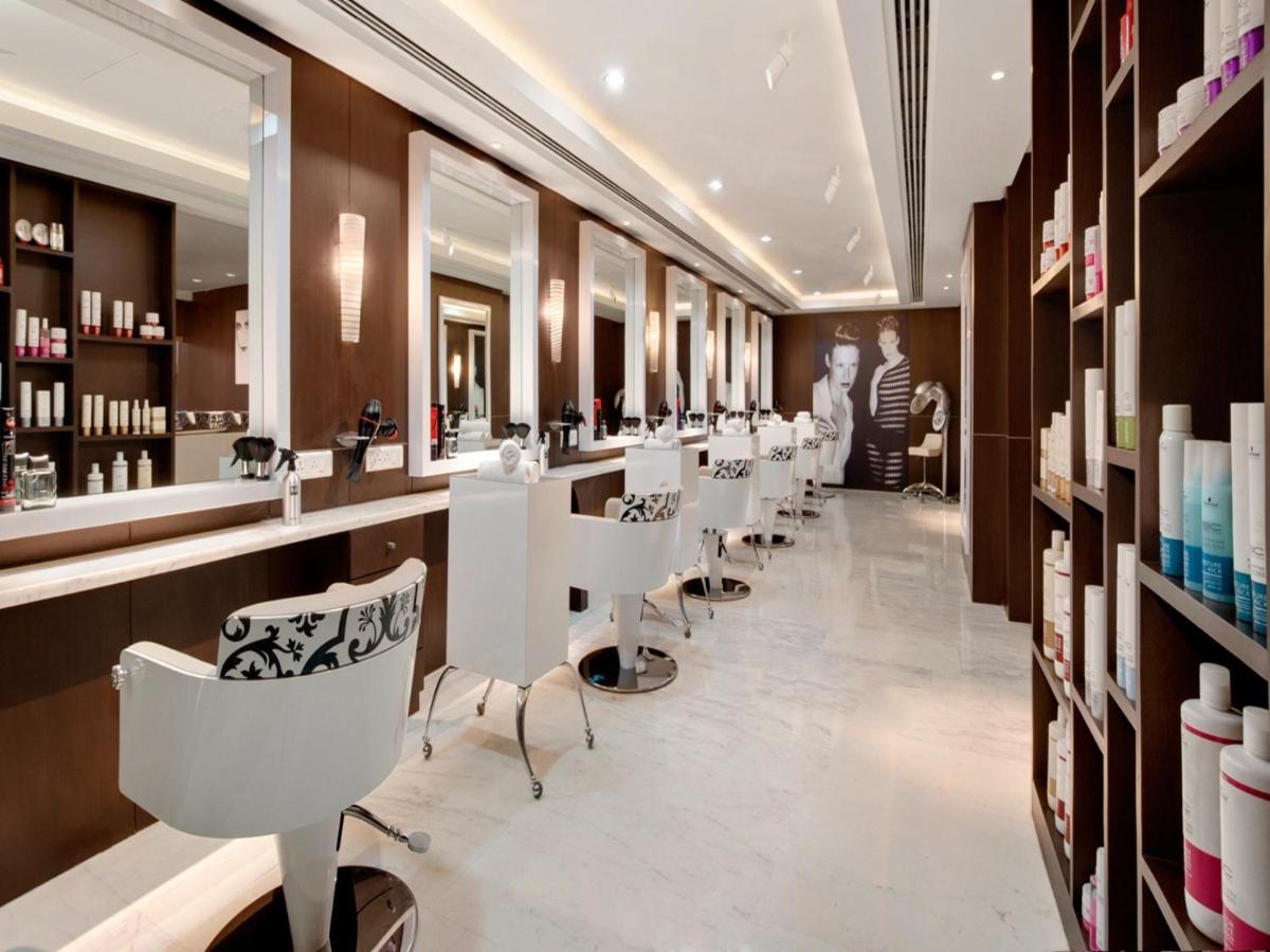 a salon with a row of white chairs and mirrors at The Leela Ambience Convention Hotel Delhi in New Delhi