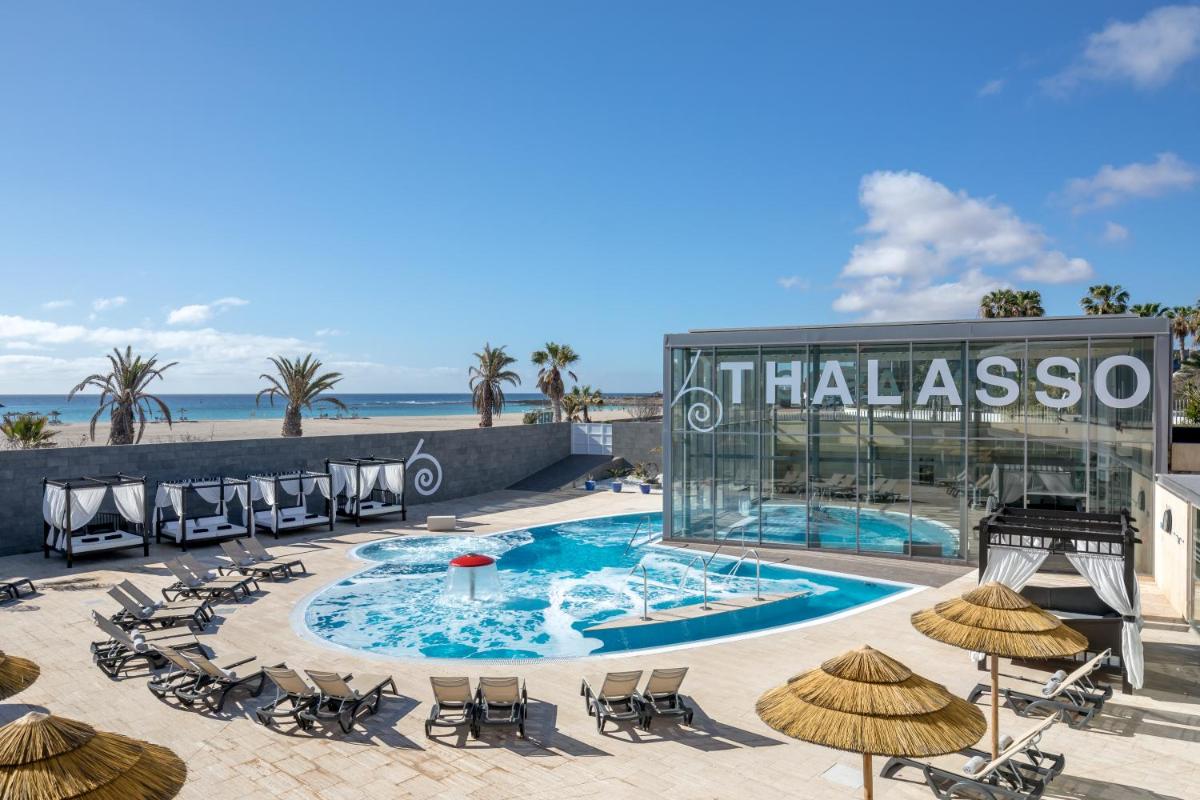 un hotel con piscina, sillas y sombrillas en Barceló Fuerteventura Mar, en Caleta de Fuste