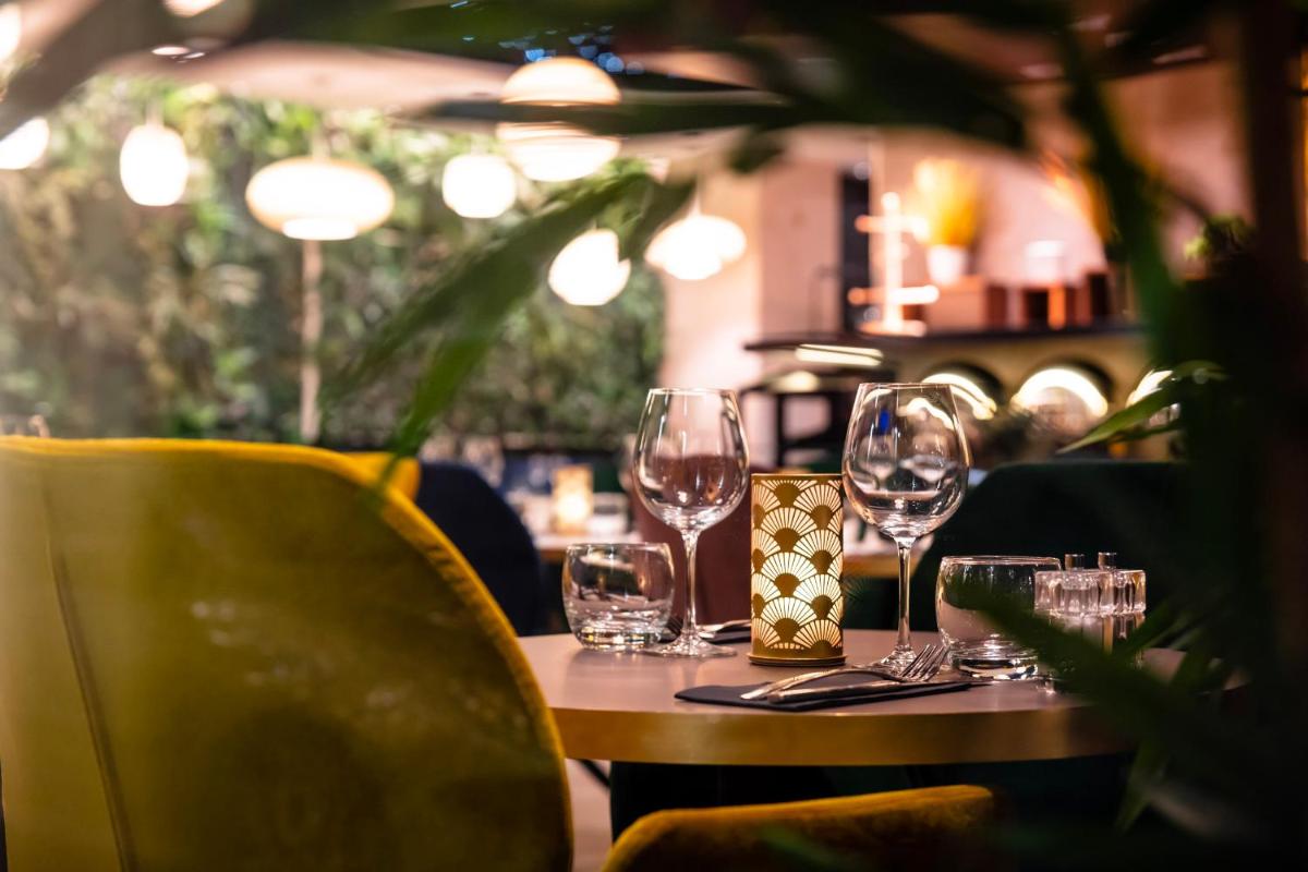 une table dans un restaurant avec des verres à vin dessus dans l'établissement voco Strasbourg Centre - The Garden by IHG, à Strasbourg