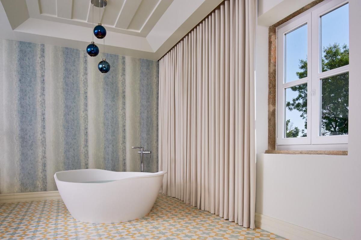 uma casa de banho com uma banheira branca e uma janela em Convento do Seixo Boutique Hotel & Spa no Fundão