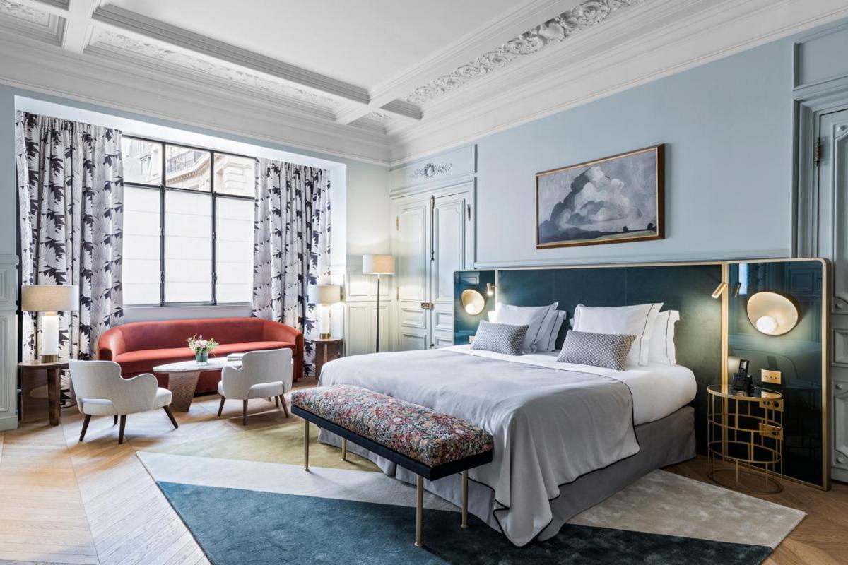 une chambre avec un grand lit et un canapé rouge dans l'établissement Grand Powers Hotel, à Paris