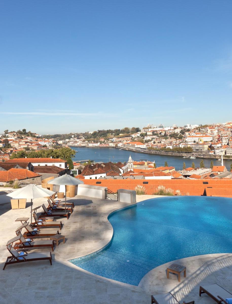 uma grande piscina com espreguiçadeiras e guarda-sóis em The Yeatman em Vila Nova de Gaia