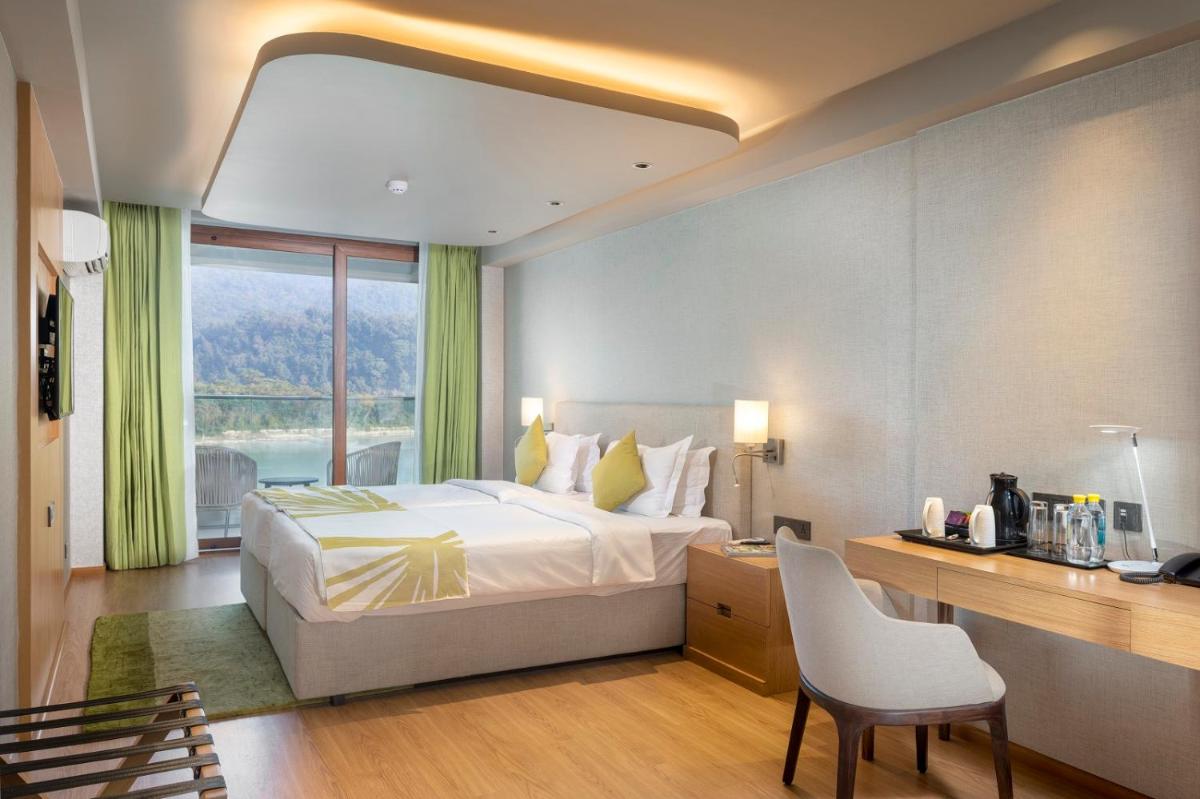 a hotel room with a bed and a desk and a window at Modi Yoga Retreat Rishikesh in Rishīkesh