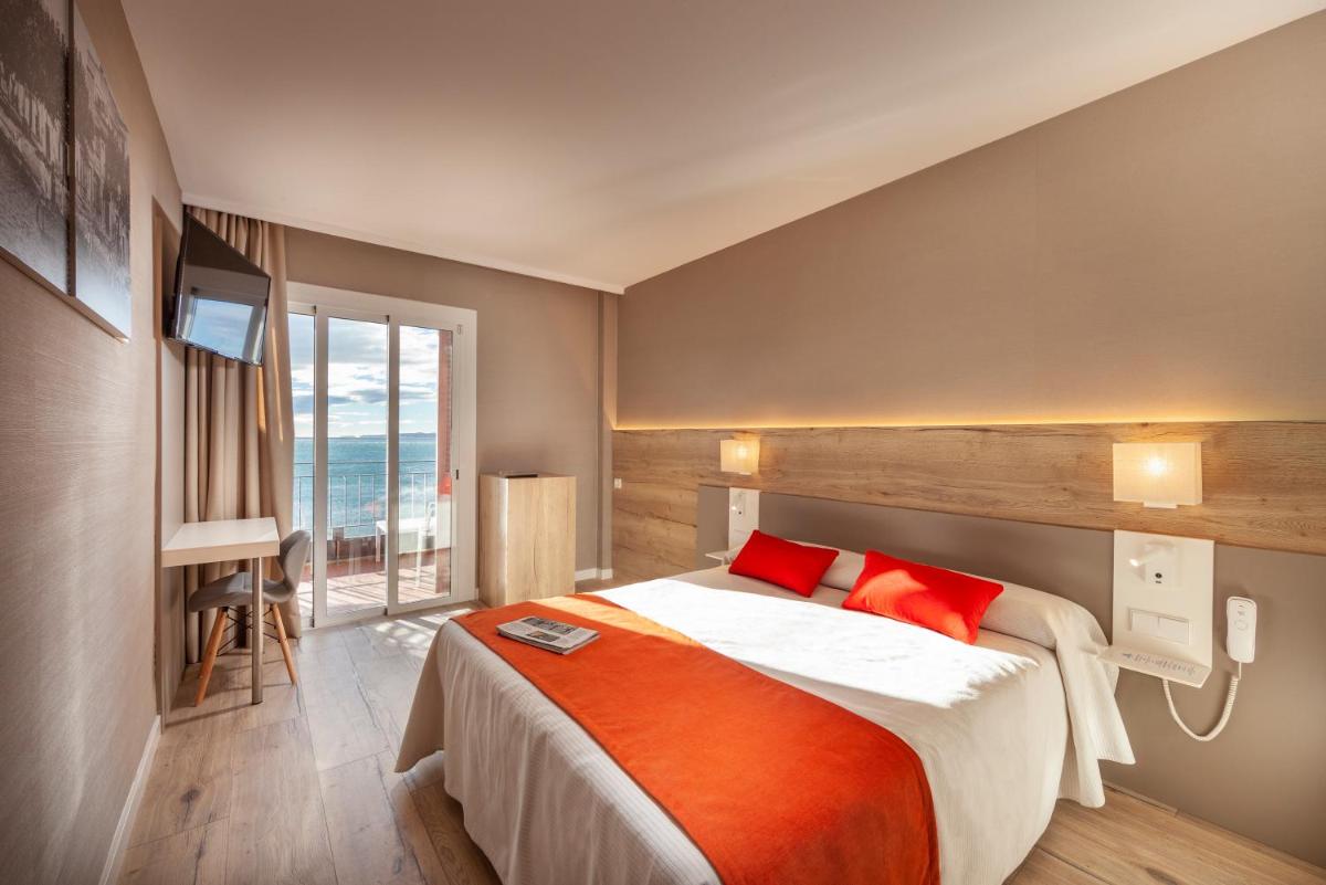 Un dormitorio con una cama grande con almohadas rojas. en Hotel Montecarlo Spa & Wellness, en Roses