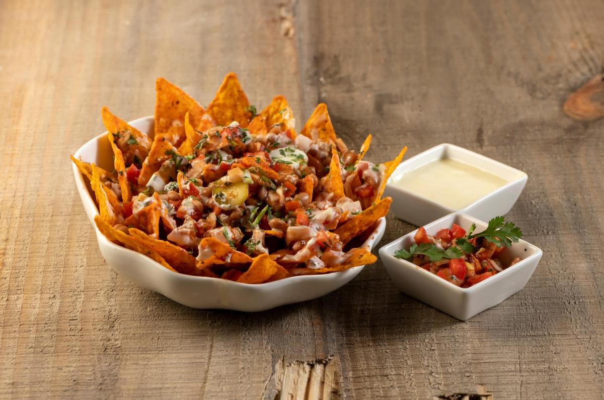 a bowl of nacho chips and a container of salsa at Modi Yoga Retreat Rishikesh in Rishīkesh