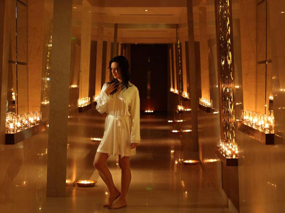 a woman in a white dress talking on a cell phone at The Lalit Mumbai in Mumbai