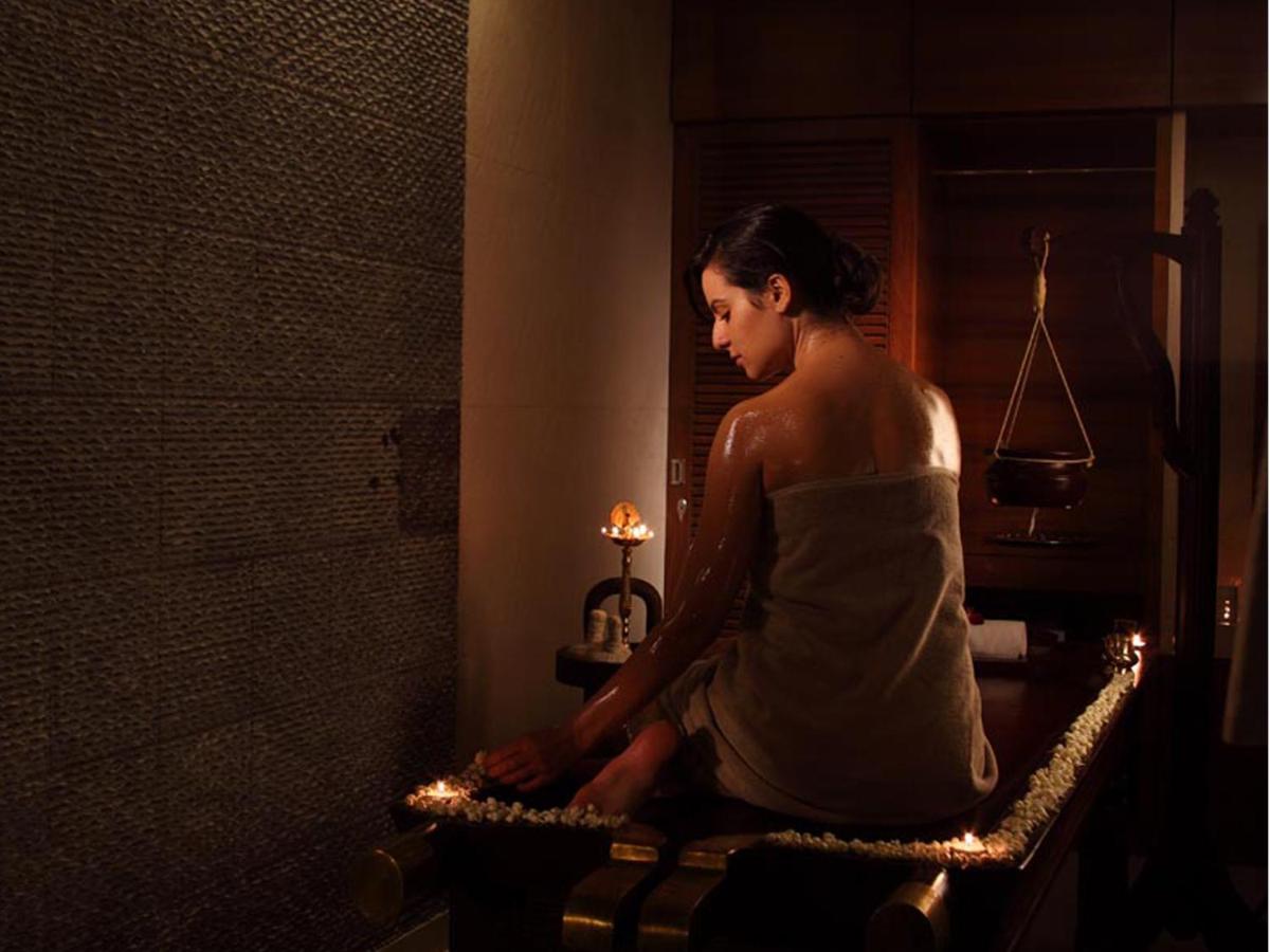a woman sitting on a bench in a bathroom with a candle at The Lalit Mumbai in Mumbai