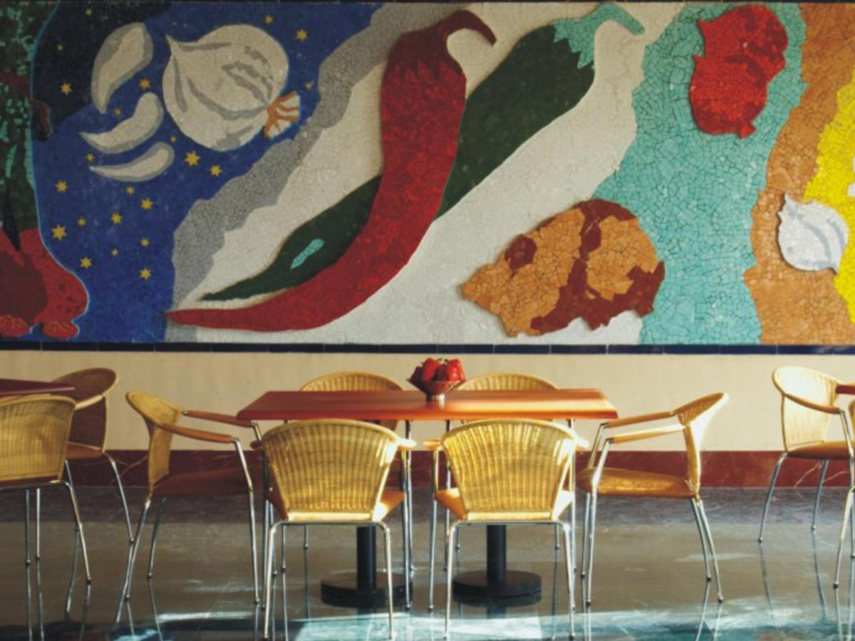 a table and chairs in front of a large painting at The Lalit Mumbai in Mumbai