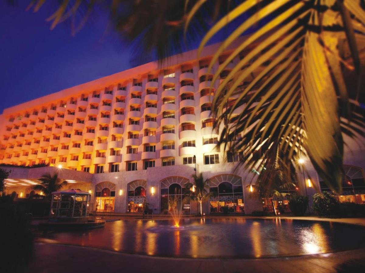 a hotel with a palm tree in front of it at The Lalit Mumbai in Mumbai