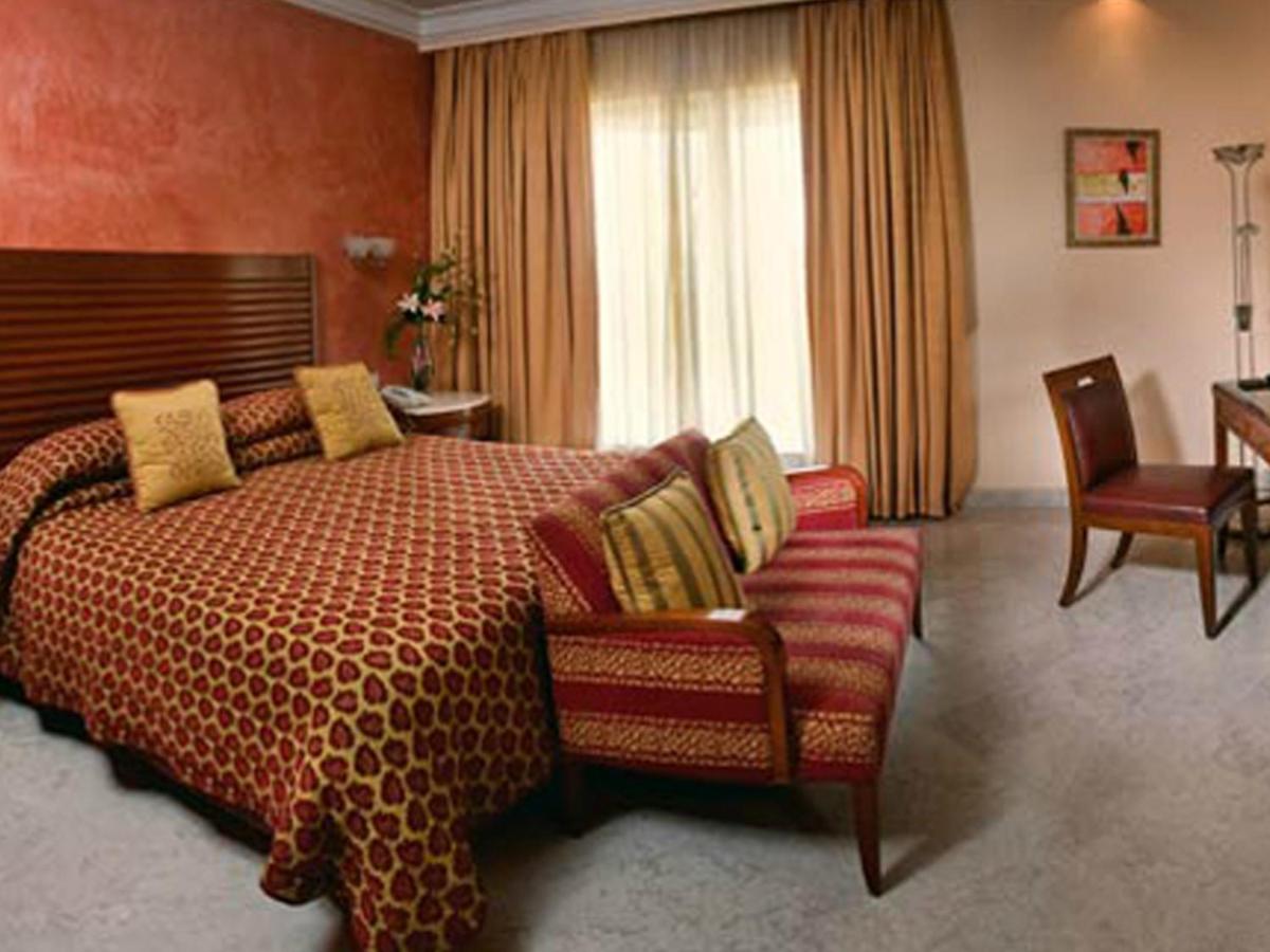 a hotel room with a bed and a chair at The Lalit Mumbai in Mumbai