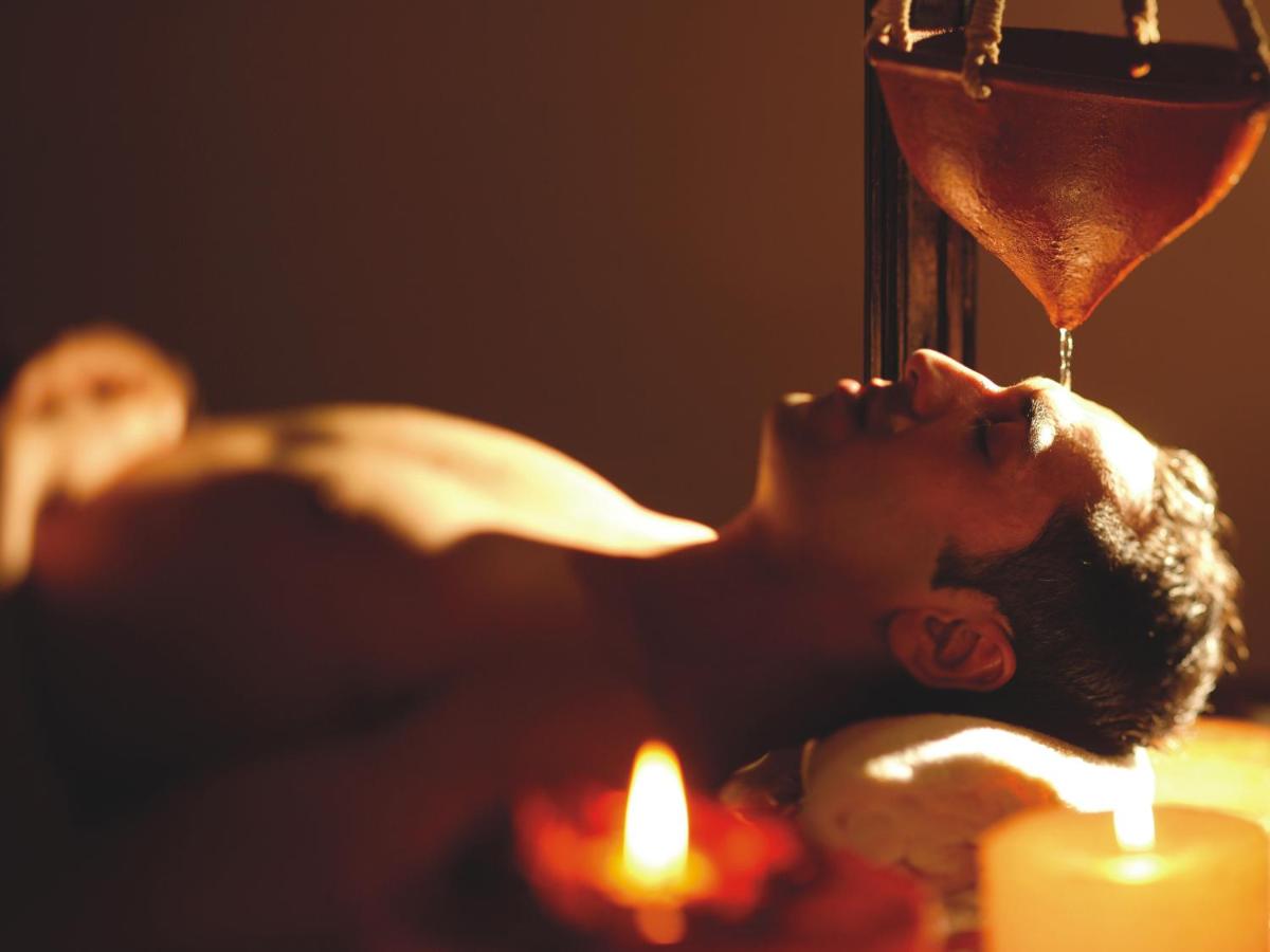 a man laying down with a glass of wine and candles at The Lalit Mumbai in Mumbai