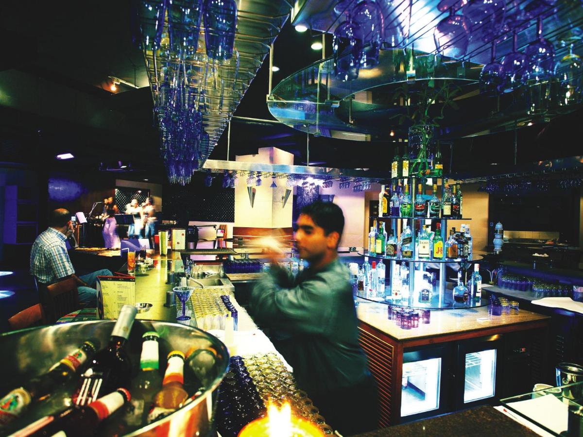 a man sitting at a bar in a restaurant at The Lalit Mumbai in Mumbai