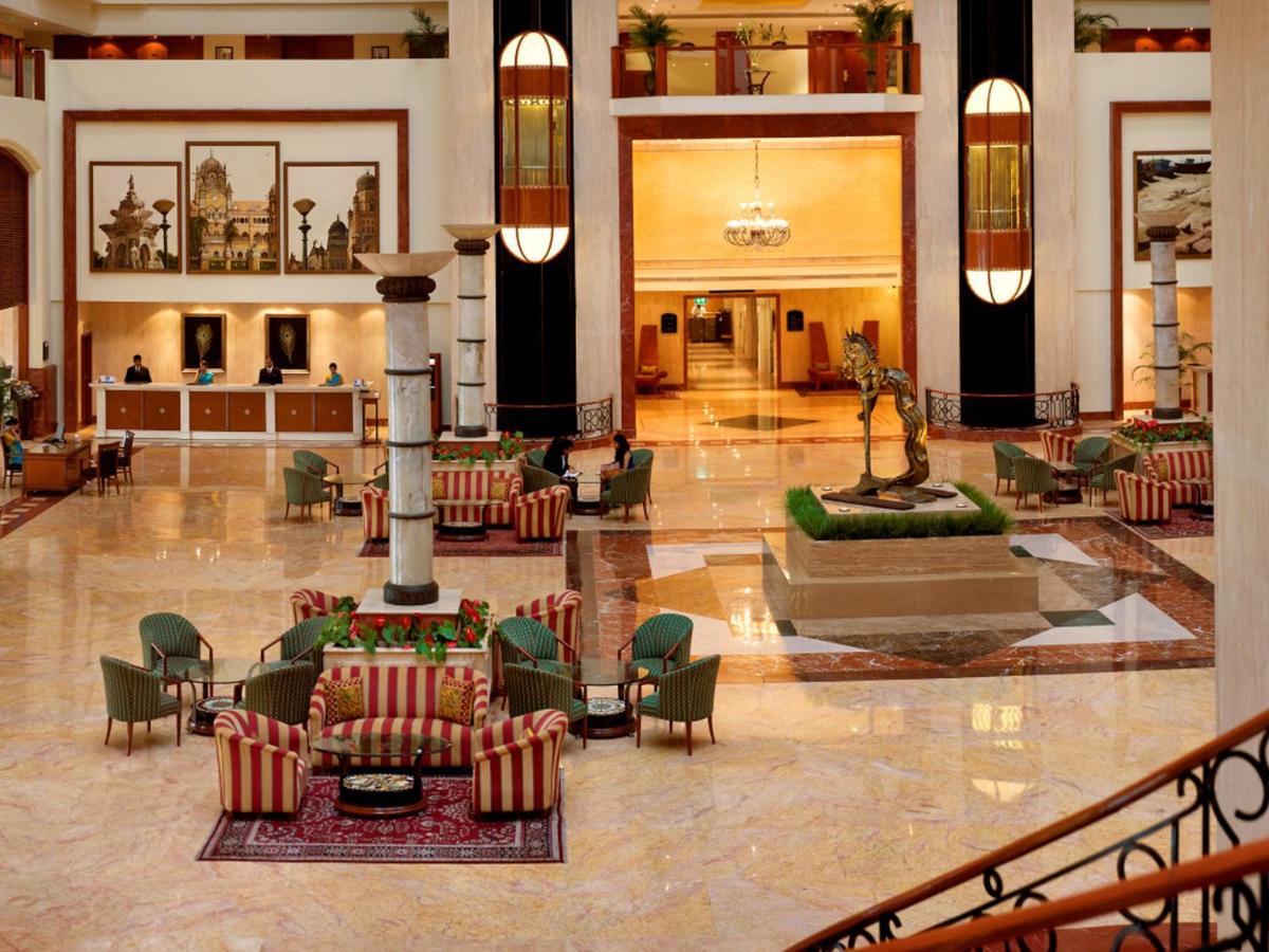 a lobby with chairs and a fountain in a building at The Lalit Mumbai in Mumbai +88 photos