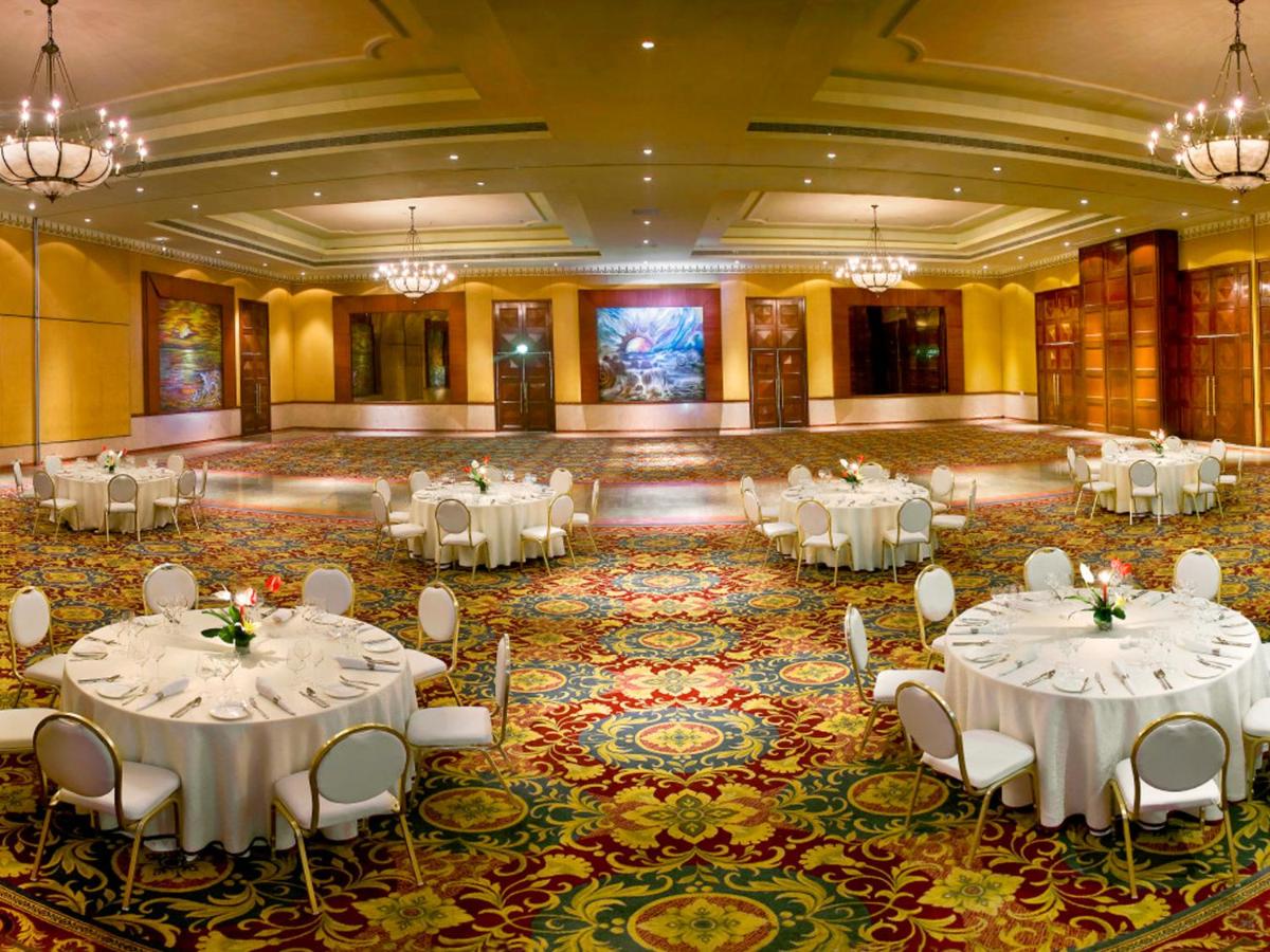 a banquet hall with white tables and chairs at The Lalit Mumbai in Mumbai