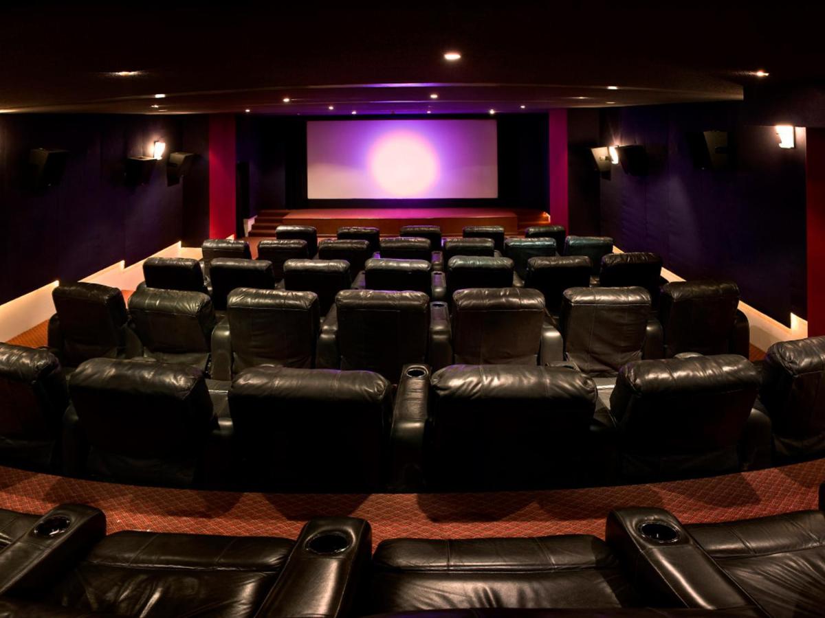 an auditorium with black leather chairs and a projection screen at The Lalit Mumbai in Mumbai