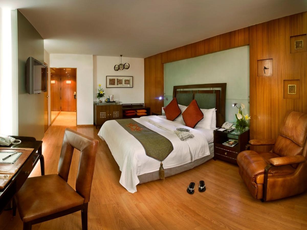 a bedroom with a bed and a desk and a chair at The Lalit Mumbai in Mumbai