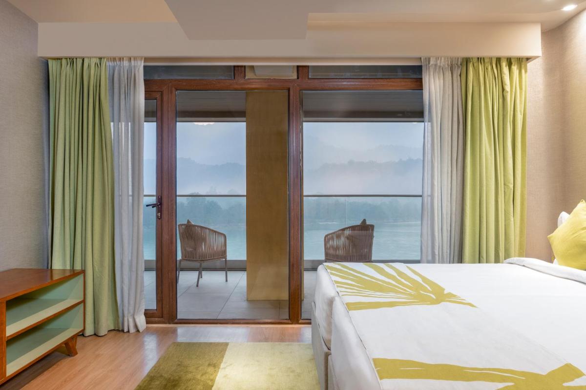 a bedroom with a bed and a balcony with a view at Modi Yoga Retreat Rishikesh in Rishīkesh