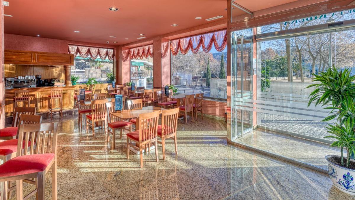 Un restaurante con mesas, sillas y ventanas. en Senator Granada, en Granada