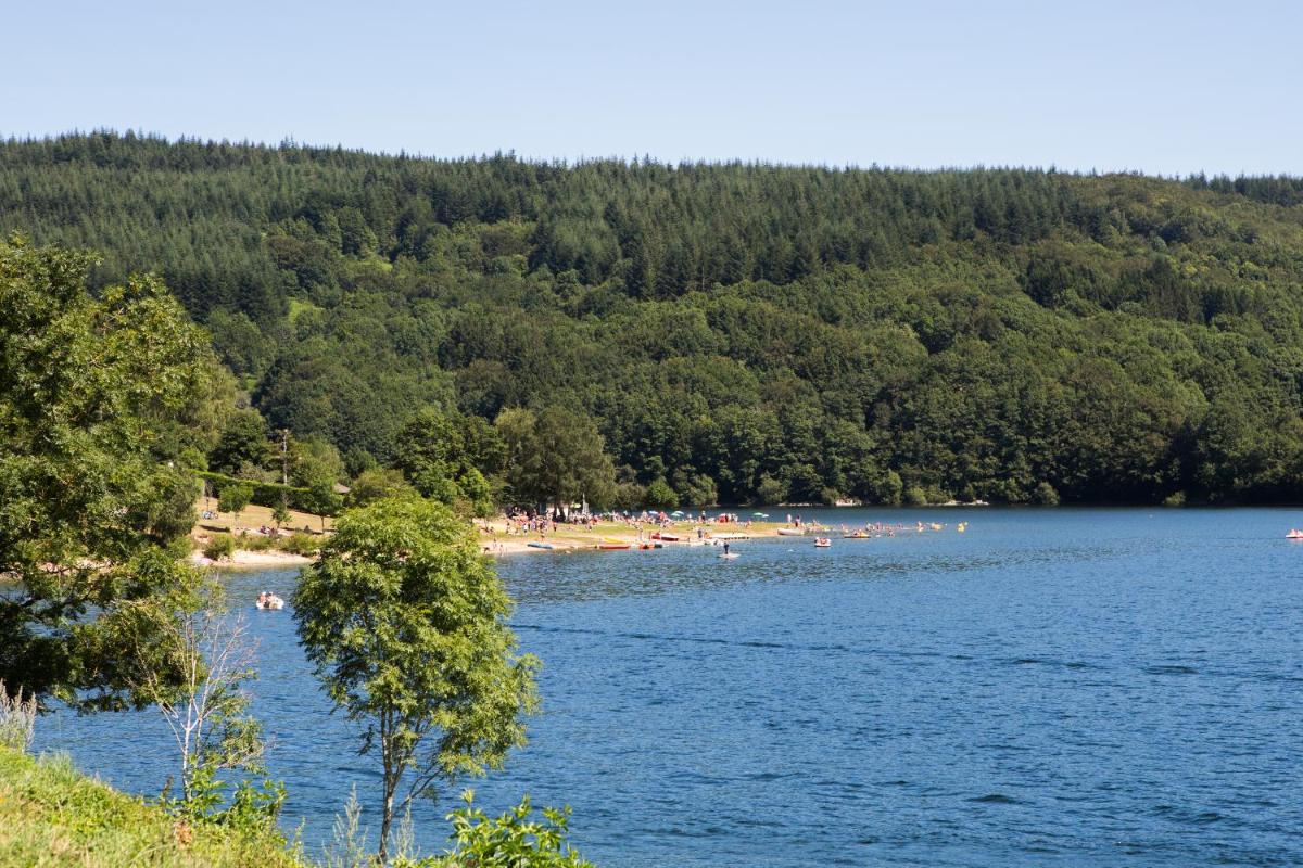 un groupe de personnes sur une plage dans un lac dans l'établissement Logis hôtel restaurant Auberge de l'Espinouse, à Fraisse-sur-Agout