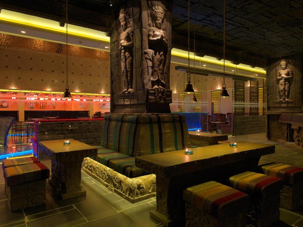 a restaurant with tables and chairs and a pillar at Sterlings Mac Hotel in Bengaluru