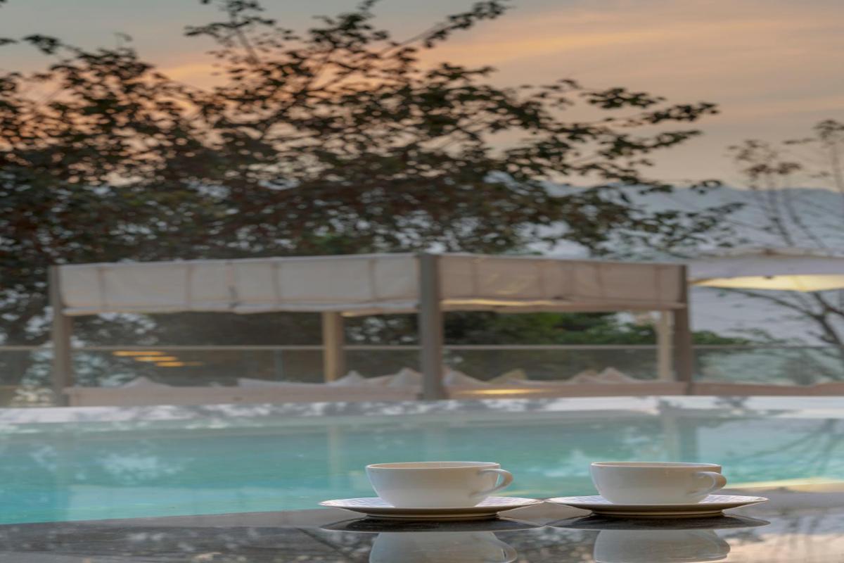 two coffee cups sitting on a table next to a swimming pool at Modi Yoga Retreat Rishikesh in Rishīkesh