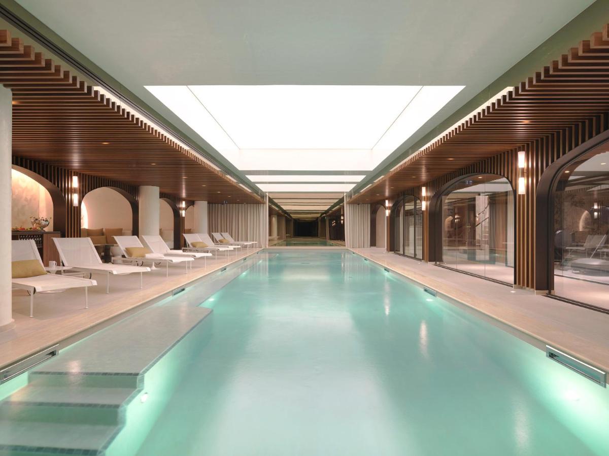 une piscine dans un immeuble avec des chaises blanches dans l'établissement Hôtel D'Aubusson, à Paris