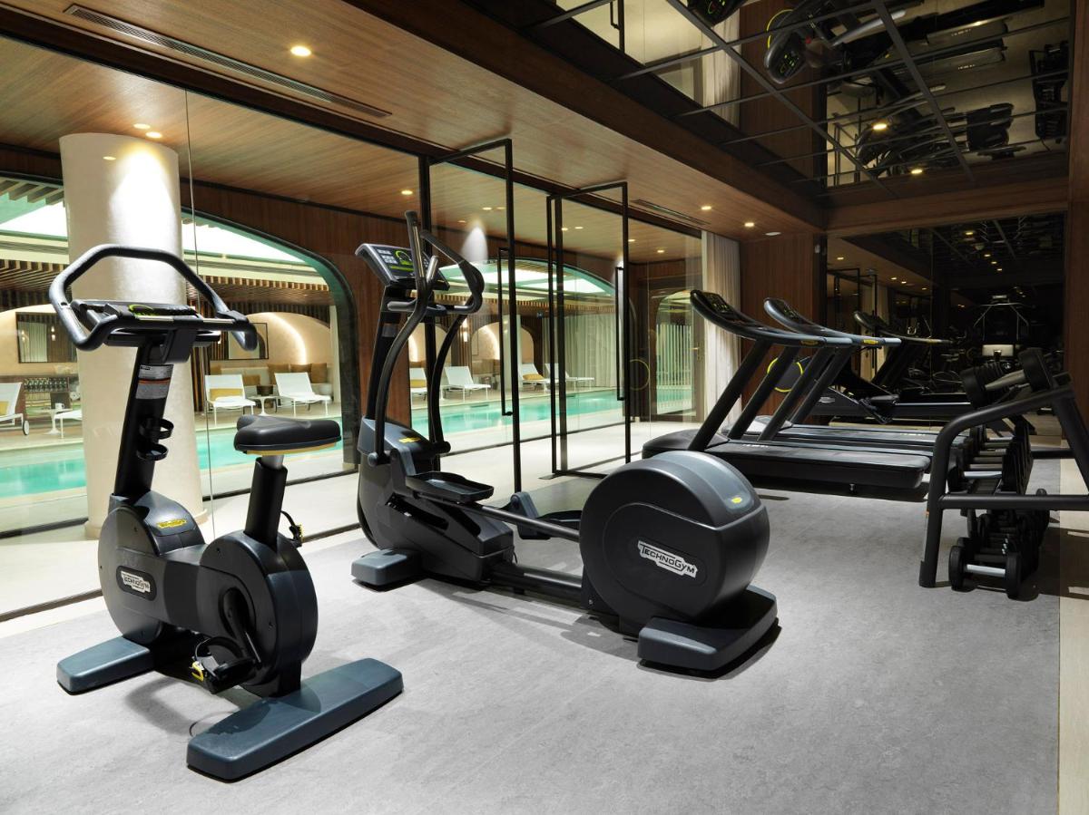 une salle de sport avec plusieurs appareils de course et une piscine dans l'établissement Hôtel D'Aubusson, à Paris