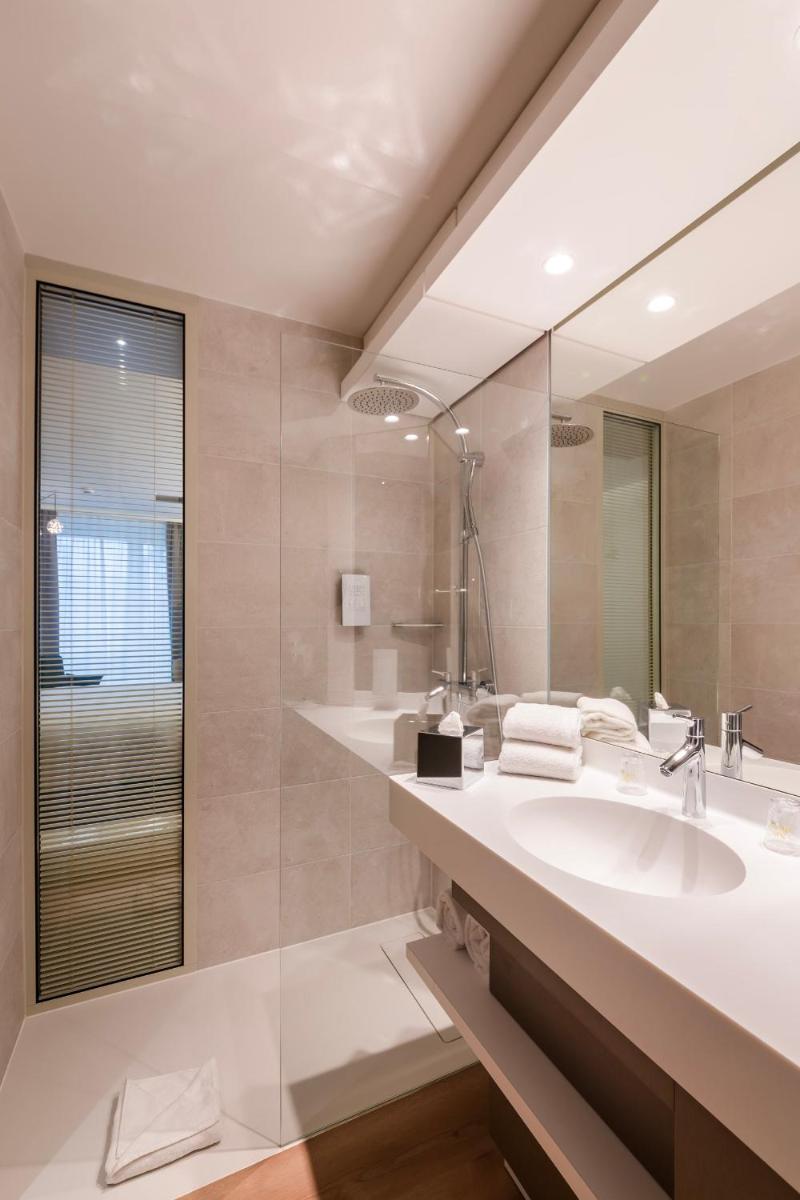 une salle de bain avec un lavabo et un miroir dans l'établissement voco Strasbourg Centre - The Garden by IHG, à Strasbourg 74 autres photos
