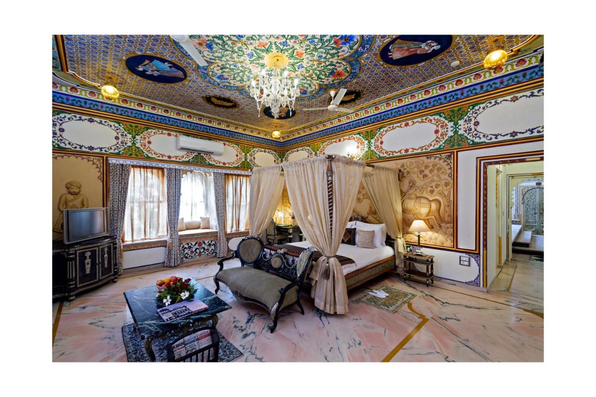 a large room with a bed and a ceiling with paintings at Chunda Palace in Udaipur