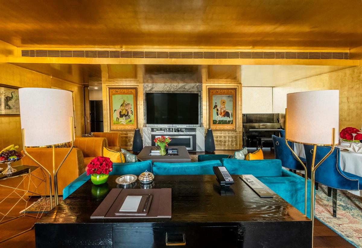a living room with blue couches and a tv at The Lodhi – A member of The Leading Hotels Of The World in New Delhi