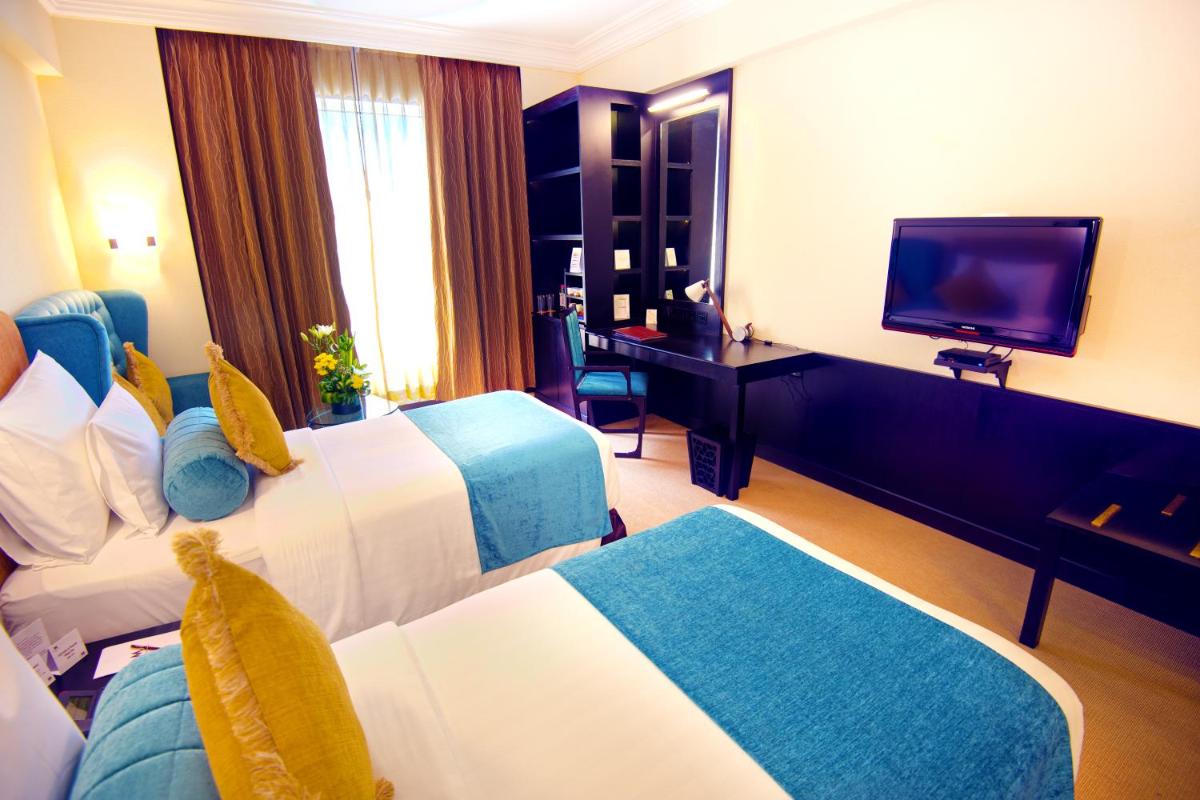 a hotel room with two beds and a flat screen tv at Sterlings Mac Hotel in Bengaluru