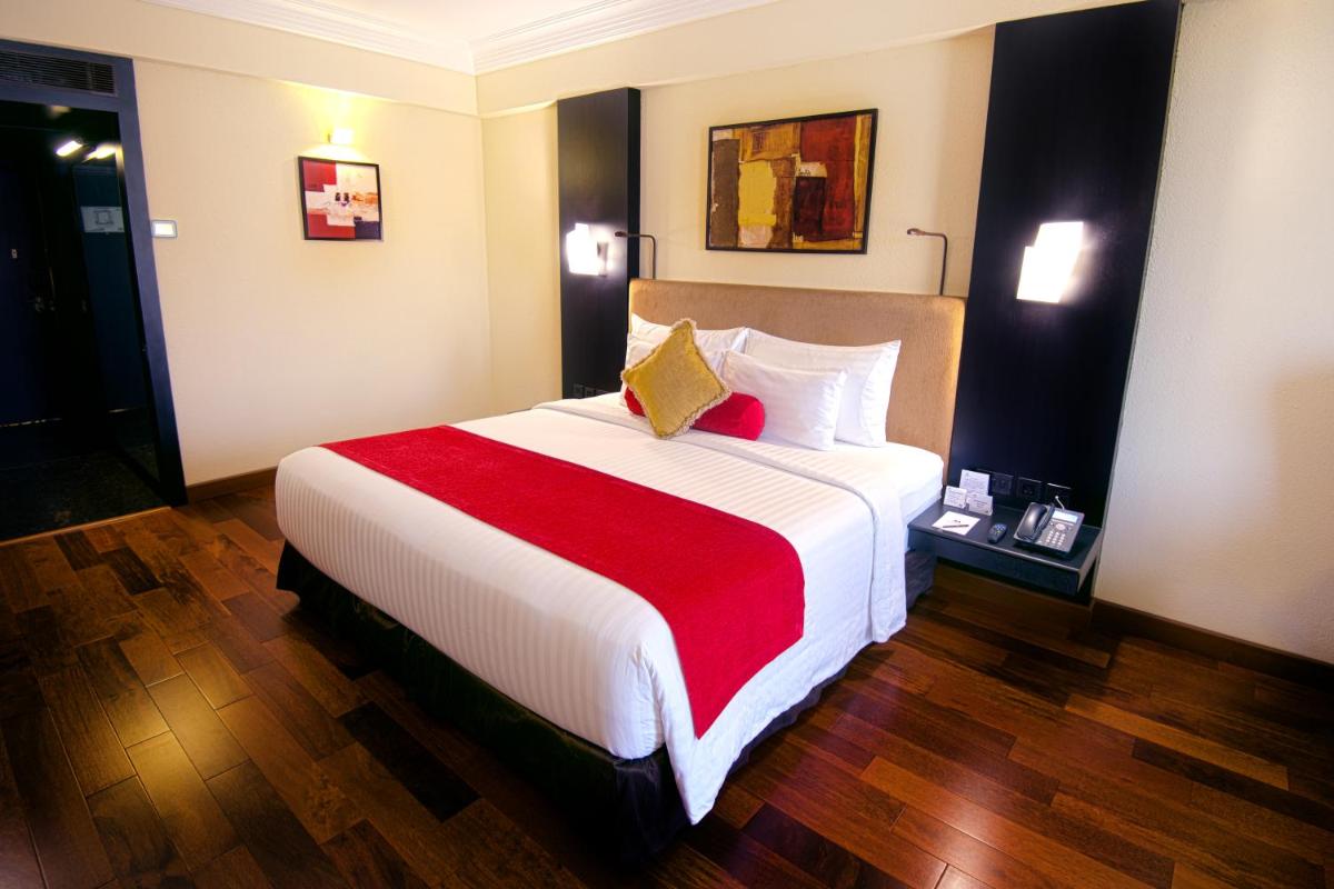 a hotel room with a large bed with a red blanket at Sterlings Mac Hotel in Bengaluru