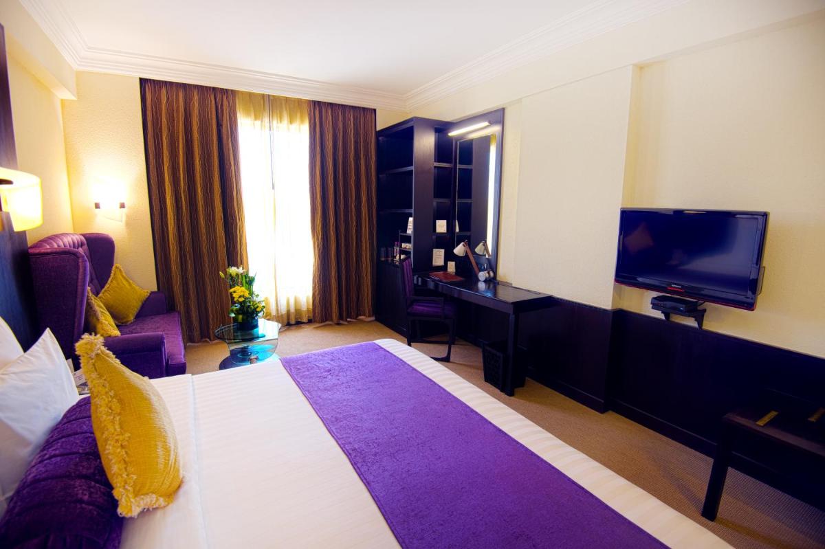 a hotel room with a bed and a flat screen tv at Sterlings Mac Hotel in Bengaluru