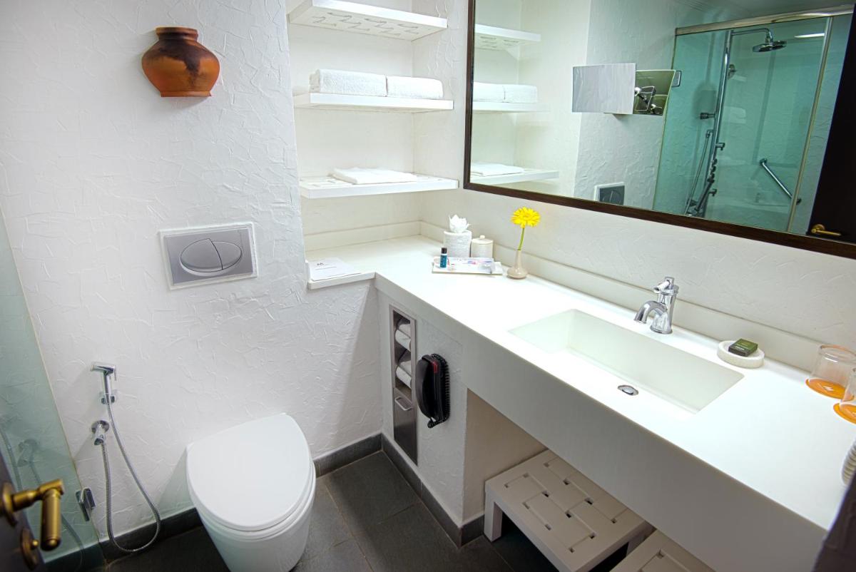a bathroom with a sink and a toilet and a mirror at Sterlings Mac Hotel in Bengaluru