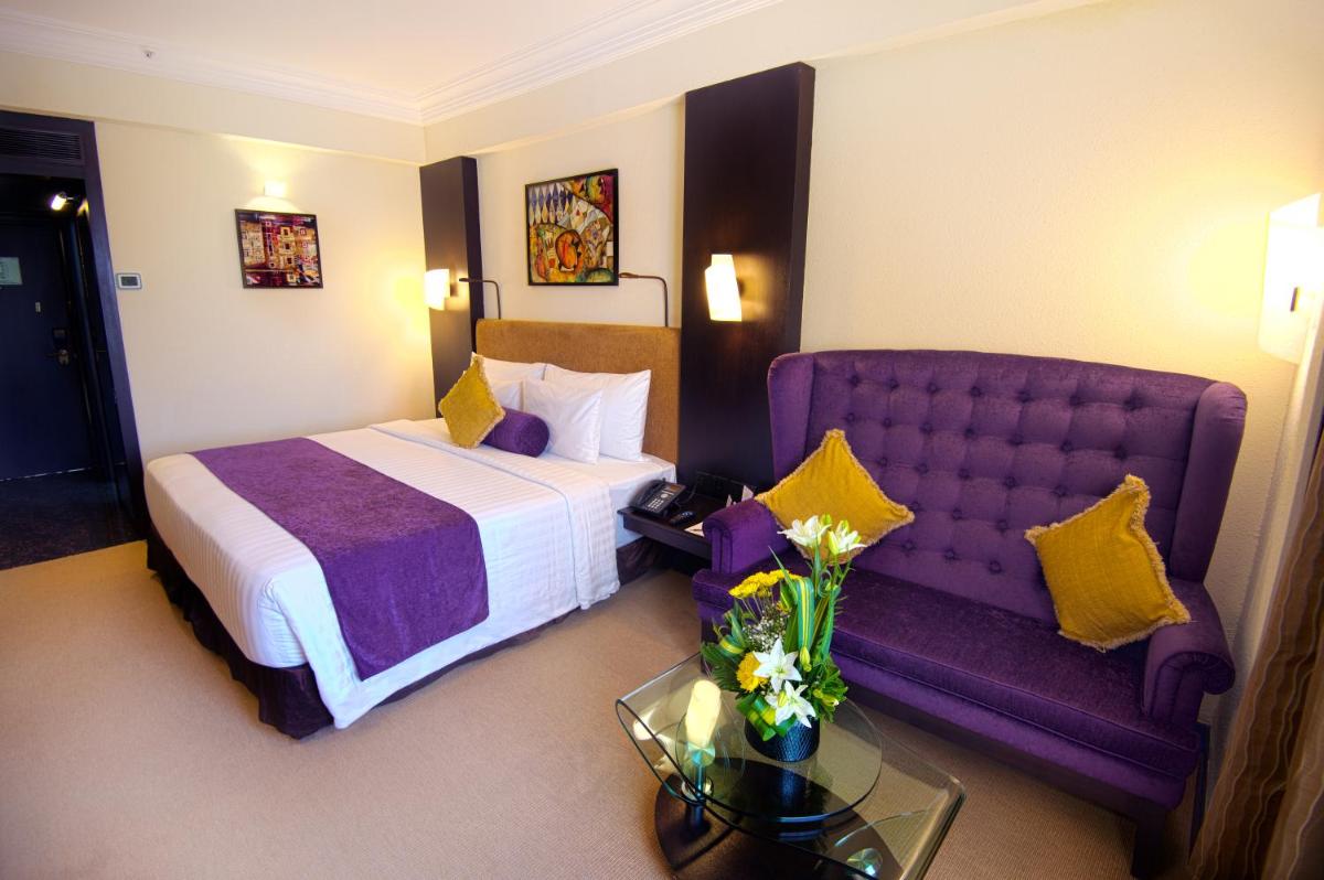 a hotel room with a bed and a purple couch at Sterlings Mac Hotel in Bengaluru