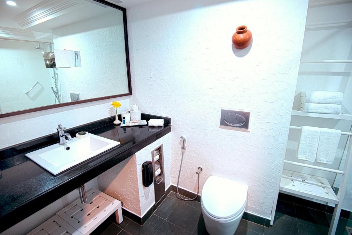 a bathroom with a sink and a toilet and a mirror at Sterlings Mac Hotel in Bengaluru