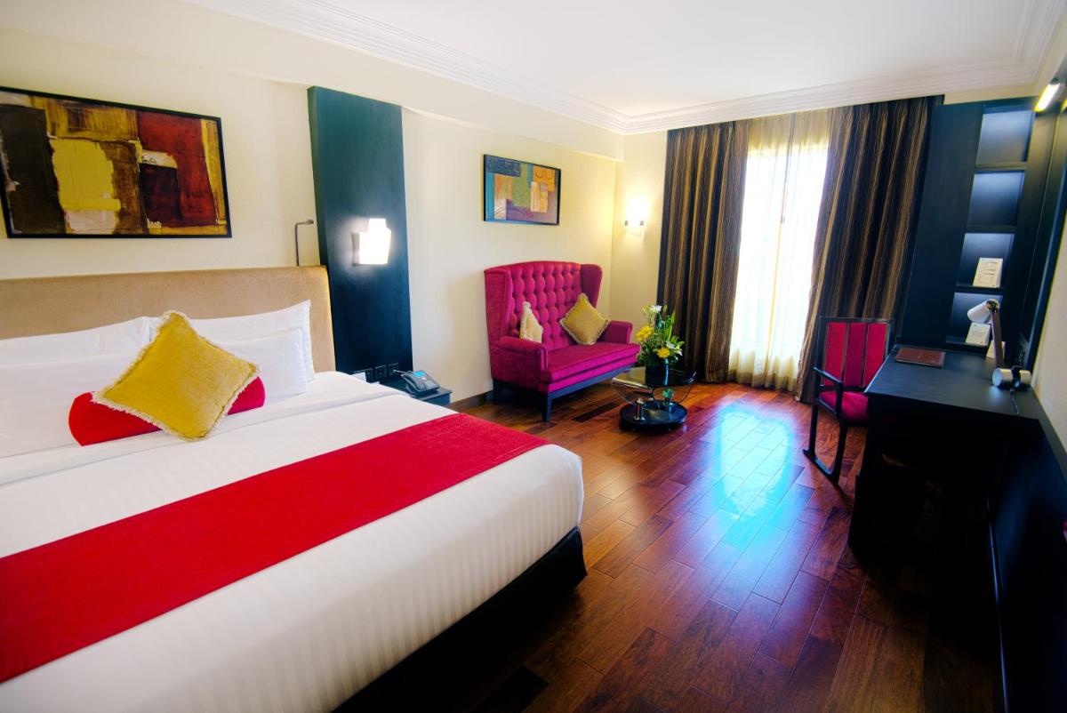 a hotel room with a bed and a desk and chair at Sterlings Mac Hotel in Bengaluru