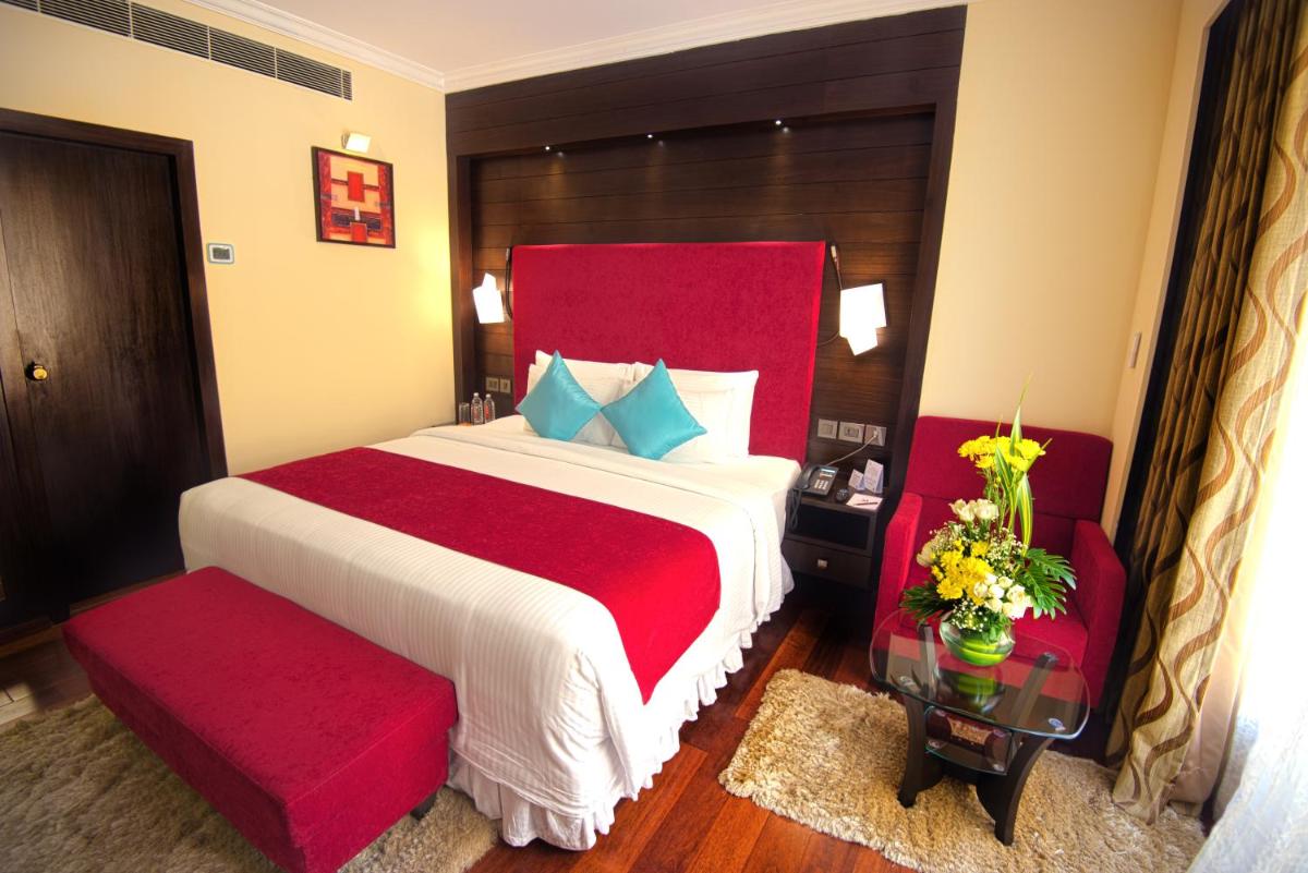 a bedroom with a large bed and two red chairs at Sterlings Mac Hotel in Bengaluru