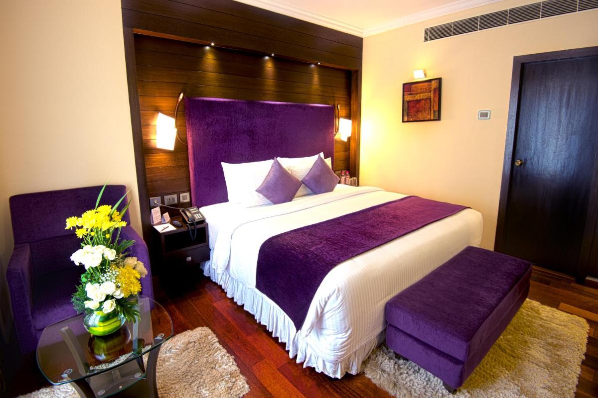 a bedroom with a large bed with a purple headboard at Sterlings Mac Hotel in Bengaluru